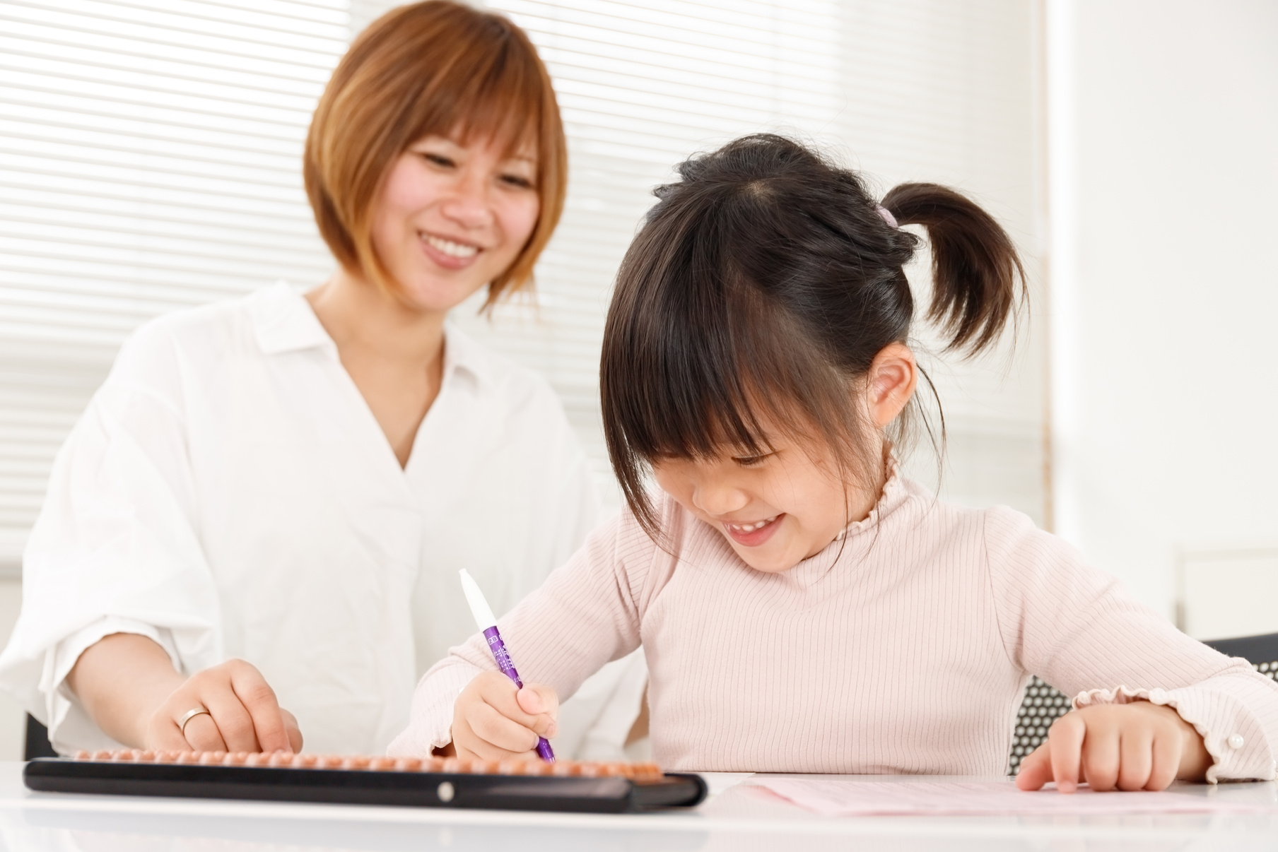 Student child and teacher in cram school or abacus classroom. An image of supporting a child while watching over it happily.